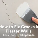 Close-up of a hand applying plaster compound to a cracked plaster wall.